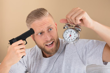 Angry Man Holding Gun And Alarm Clock
