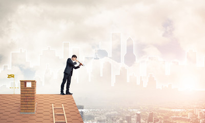 Engineer man standing on roof and looking in spyglass. Mixed med