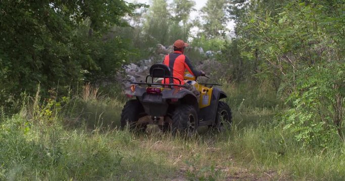 Man driving quad bike 4k video. All-terrain vehicle riding up hill. ATV in forest. Four-wheeler quadricycle transport and extreme sport.