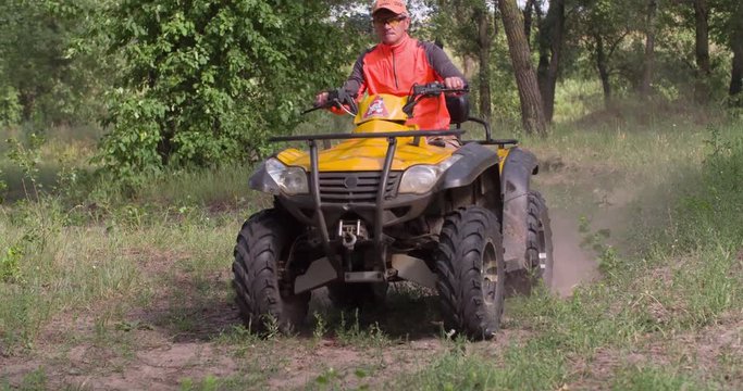 Man driving quad bike 4k slow-motion video. All-terrain vehicle riding ATV in forest. Four-wheeler quadricycle transport and extreme sport.