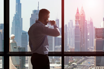 Businessman Drinking Coffee And Looking At City Skyline