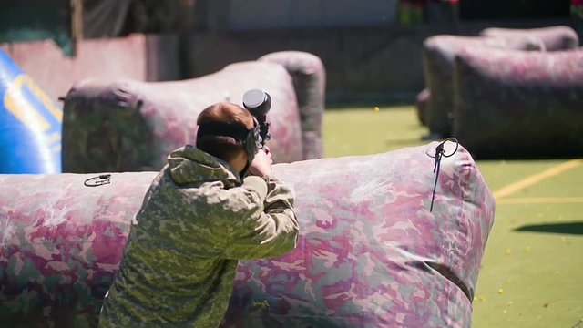 Paintball player aiming and shooting HD game slow-motion video. Man with gun hitting on playing field venue. Sport action war battle fighting