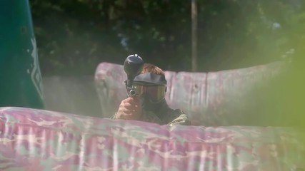 Paintball player aiming and shooting target HD game slow-motion POV video. Man with gun hitting to camera on playing field. Ball flying and painting camera