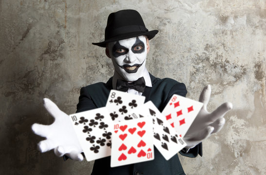 Evil clown playing with poker cards