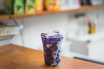 Ice Butterfly pea Tea with milk Cream on wooden table with soft background