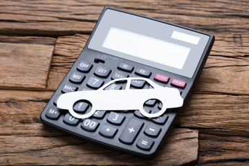Paper Car On Calculator At Wooden Table