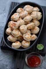 Roasted russian pelmeni served in a frying pan, selective focus, vertical shot