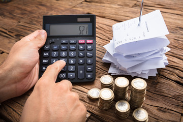 Businessman Using Calculator By Coins And Bills On Table