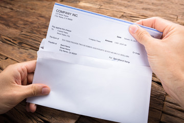 Businessman's Hands Holding Cheque At Table