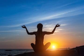 Silhouette of a beautiful yoga woman at sunset.