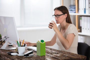 Woman Drinking Juice While Using Computer