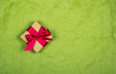 Gift box with satin bow on a pale paper background. Backgrounds and textures. Copy space