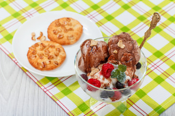 Chocolate and white ice cream in a glass with raspberry and currant berries and mint leaves on checkered napkin