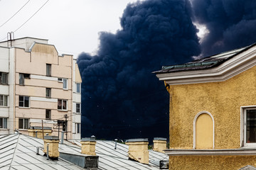 Black smoke from a fire is over the roofs of houses