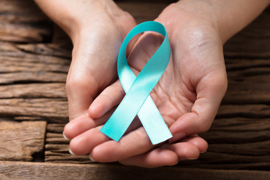 Human Hand Showing Teal Ribbon To Support Breast Cancer Cause