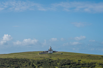 Fototapeta na wymiar An isolated Belle Tout lighthouse sits amongst the rolling hills of the South Downs National Park cliff top coastal path