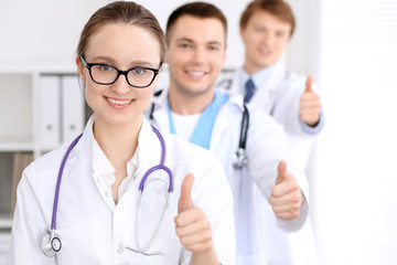 Happy doctor woman with medical staff at the hospital, thumbs up