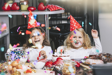 Two happy little girls child celebrating a birthday with cake at the table is lovely and beautiful
