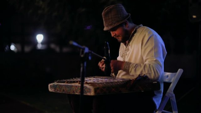 Close-up of a man's hand plays a dulcimer at night. Ancient Ukrainian Instruments
