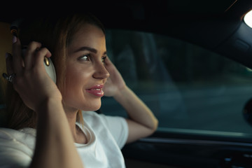 Luxury woman listen music with headphones in her comfortable car