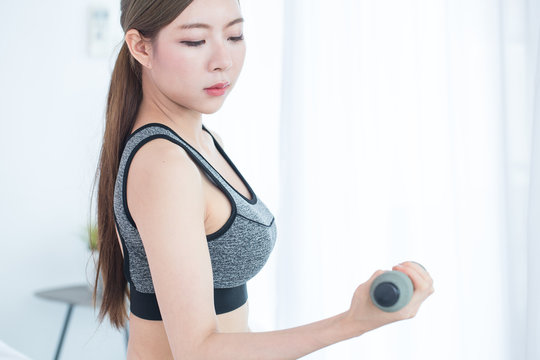 Young Fitness Asian woman doing exercises with dumbbells, workout in bedroom, fitness, training and lifestyle concept