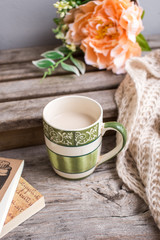 a cup of cofffee on the wood with scarf and books