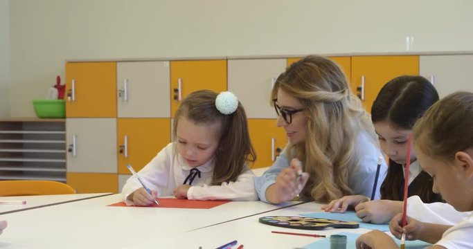 Teacher and a school girl painting at the creative lesson. High quality 4k footage