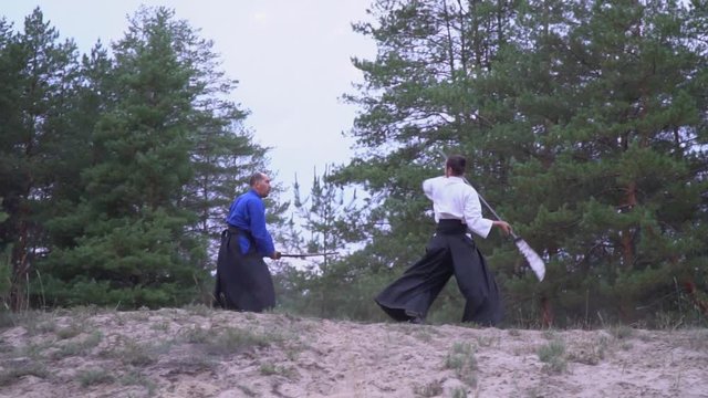 A strained samurai in a white black kimono spins a halberd and attacks a samurai with a katana, slow motion