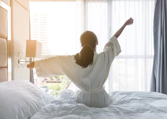 Fotobehang Gemakkelijke levensstijl jong Aziatisch meisje dat & 39 s ochtends wakker wordt en uitrust en ontspant in een hotelkamer voor een wereld luie dagconcept © Chinnapong
