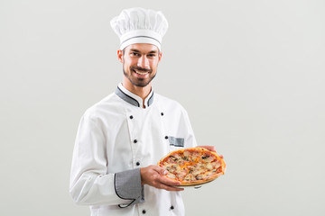 Chef holding pizza on gray background.