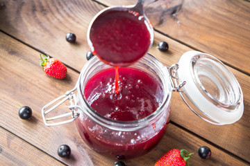Pouring homemade berry jam into a jar