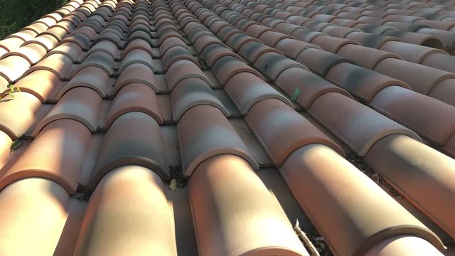 Pretty French red clay roof tiles in time lapse. The camera pans up following the disappearing shadows as the sun climbs higher in the sky