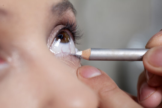 makeup artist applied eye penicl on the eye of the client
