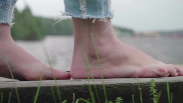 Woman's bare feet making little steps on wooden path