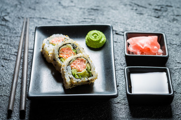 Tasty sushi made of salmon and avocado on black rock