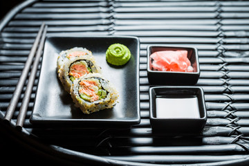 Delicious sushi with wasabi and soy sauce on black table