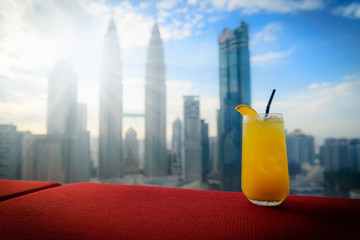 Fresh orange juice on red table with Kuala lumpur city skyline in Malaysia.