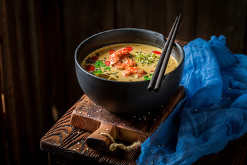 Closeup of hot Tom Yum soup in black bowl
