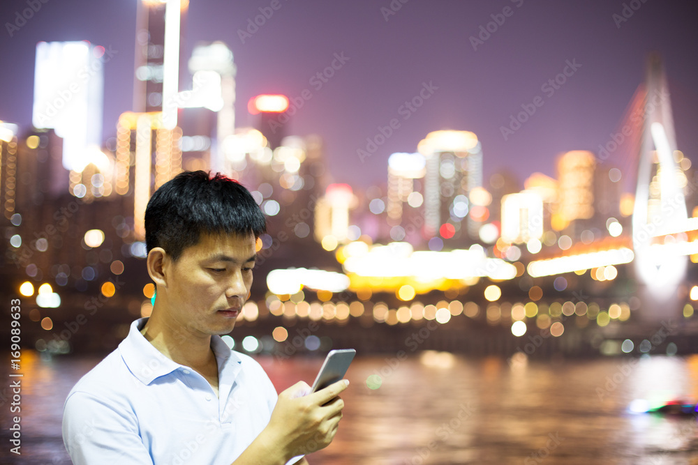 Wall mural young man with mobile phone and cityscape of modern city