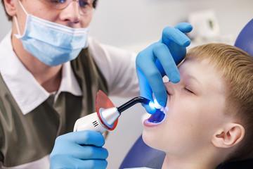 Male dentist examines the teeth of the patient cheerful boy.