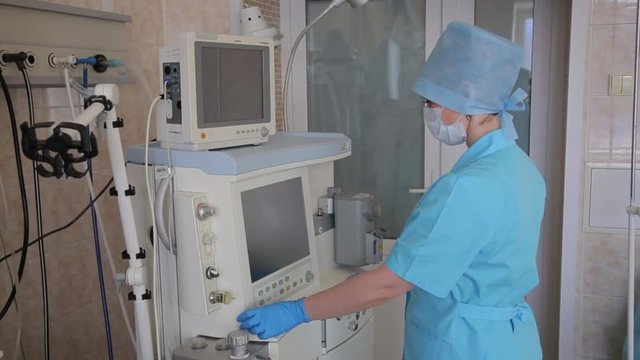 Woman nurse prepares electronic innovative apparatus for surgical operation