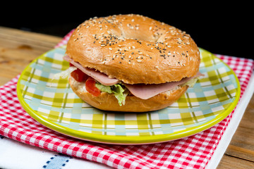 Bagel with fresh cheese and fresh lettuce on napkin