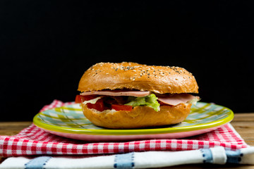 Bagel with fresh cheese and fresh lettuce on napkin