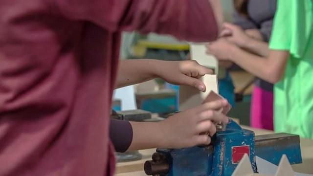 Boys are chiselling wood when designing objects made from wood. They are having a craft class.