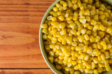 Flat lay above bowl with boiled corn on the wooden planks table