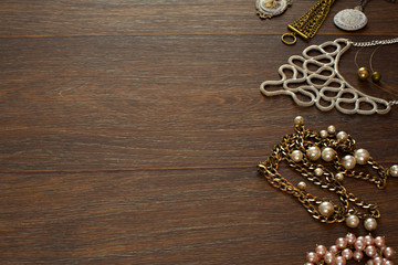 Decorative composition of women's jewelry on wooden dark background.