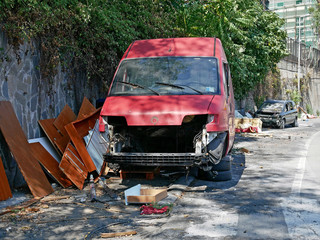 Wreck of an abandoned red van on the road