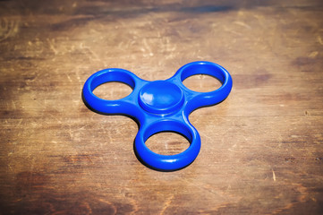 Blue fidget spinner isolated on wooden table.