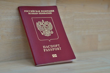 Red Russian passport on the wooden surface with captions Passport and Russian Federation in Cyrillic alphabet