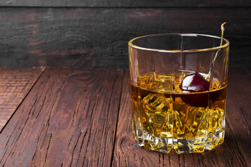 Cocktail from whisky with cherry on a wooden background. Copy space. Food background